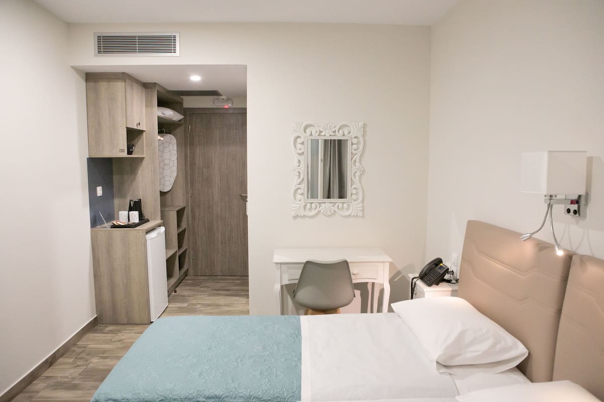 Ein Hotelzimmer mit Bett, Schreibtisch, Stuhl, Kleiderschrank und Spiegel.