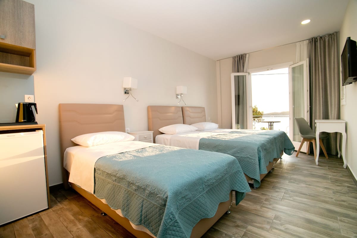 Ein Hotelzimmer mit zwei Betten, einem Schreibtisch, einem Stuhl, einem Fernseher und einem Fenster mit Vorhängen.