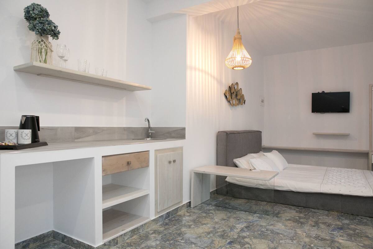 Ein modernes Schlafzimmer mit Bett, Nachttisch und einem an der Wand befestigten Fernseher.