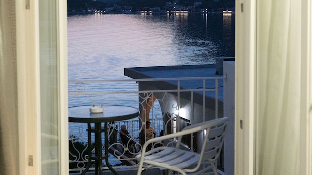 A balcony with a table and chairs, overlooking a body of water and a mountainous landscape. - Hyperion Hotel Kalymnos (Kalymnos)