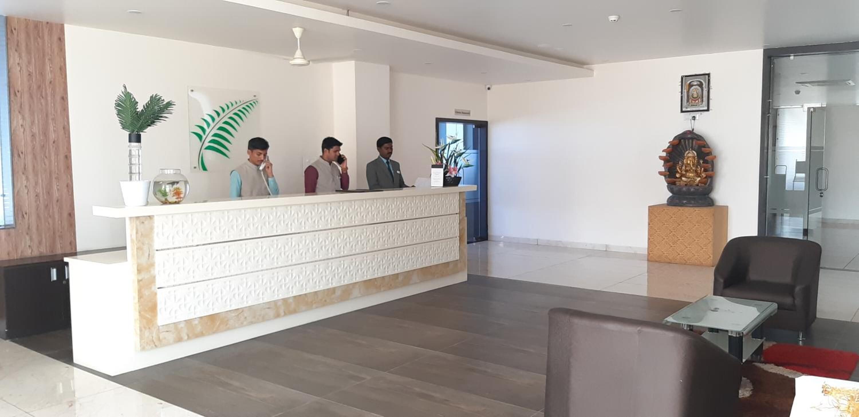 A reception area with a reception desk, a potted plant, a fishbowl, and a statue.