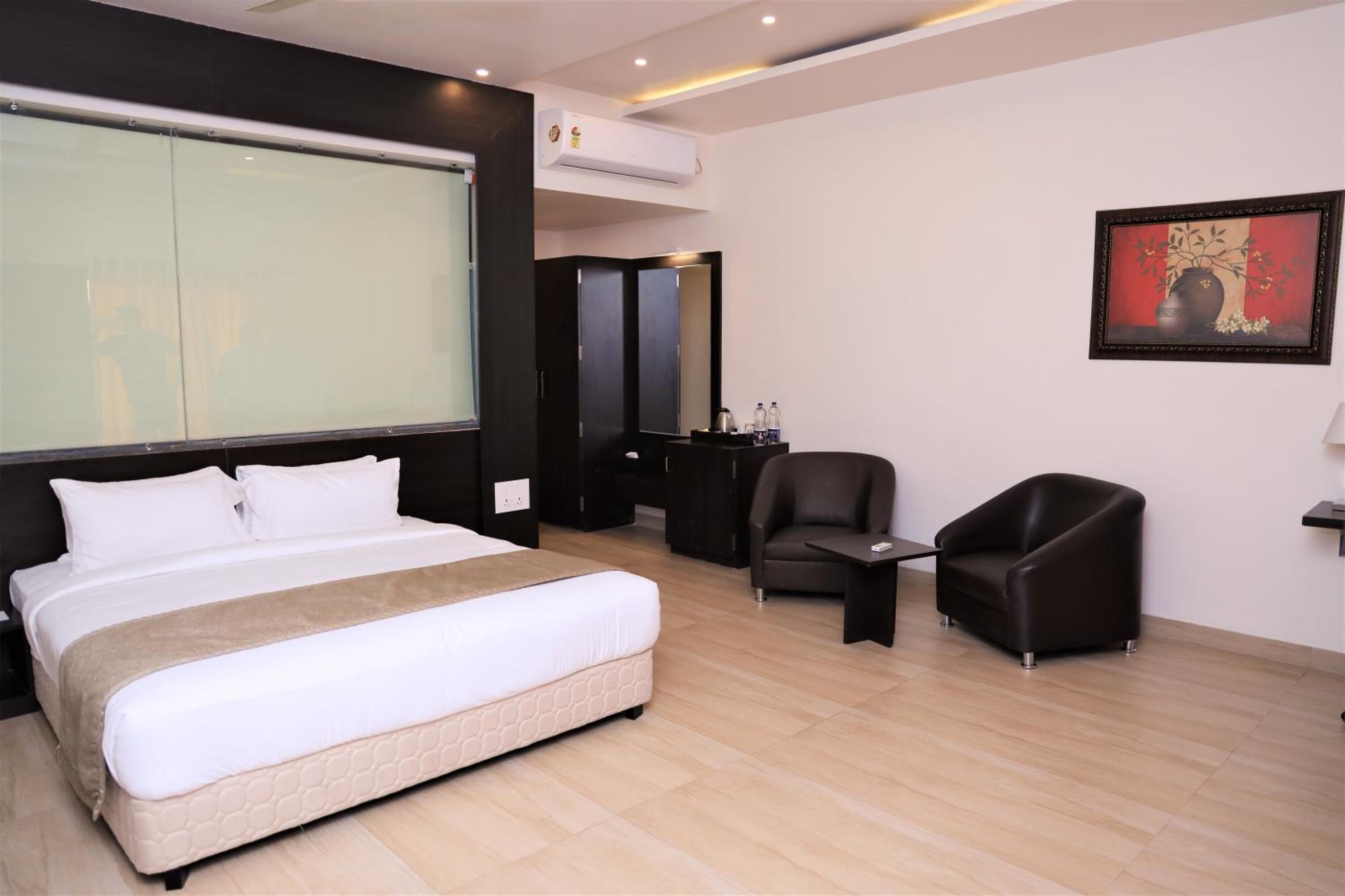 Una habitación de hotel moderna con una cama grande, un escritorio, una silla y una obra de arte enmarcada en la pared.