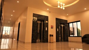 A modern lobby with a polished floor, two elevators with black granite walls, a large window, and a ceiling light fixture. - The Fern Residency Parbhani (Parbhani)