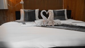 Una cama cuidadosamente tendida con una toalla dispuesta en forma de corazón y un diseño de almohada blanco y negro.