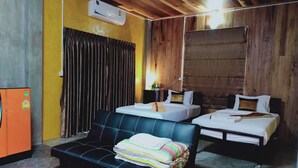 Una habitación con dos camas, un sofá, aire acondicionado y un pequeño armario naranja.