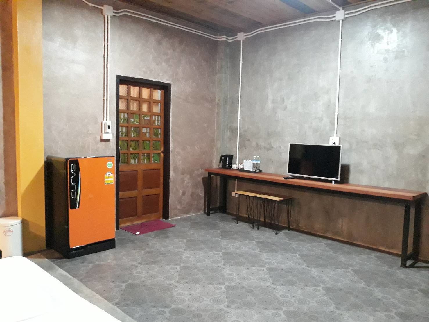 Ein kleines Zimmer mit Küchenzeile, Fernseher und einer Tür mit Gittermuster.