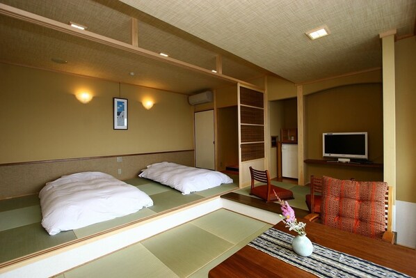A room with two beds, a TV, and a small table with a vase.