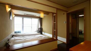 A hotel room with a bed, bedside table, and a window with curtains.