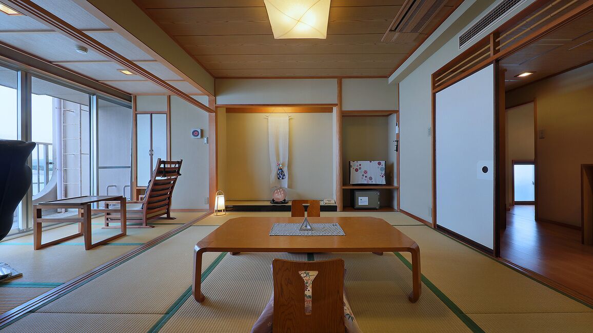 Een traditionele Japanse kamer met tatami vloerbedekking, een lage tafel met stoelen en schuifdeuren.