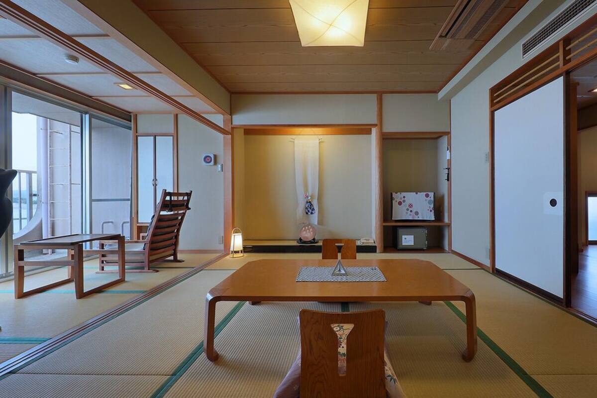 Een traditionele Japanse kamer met tatami vloerbedekking, een lage tafel met stoelen en schuifdeuren.