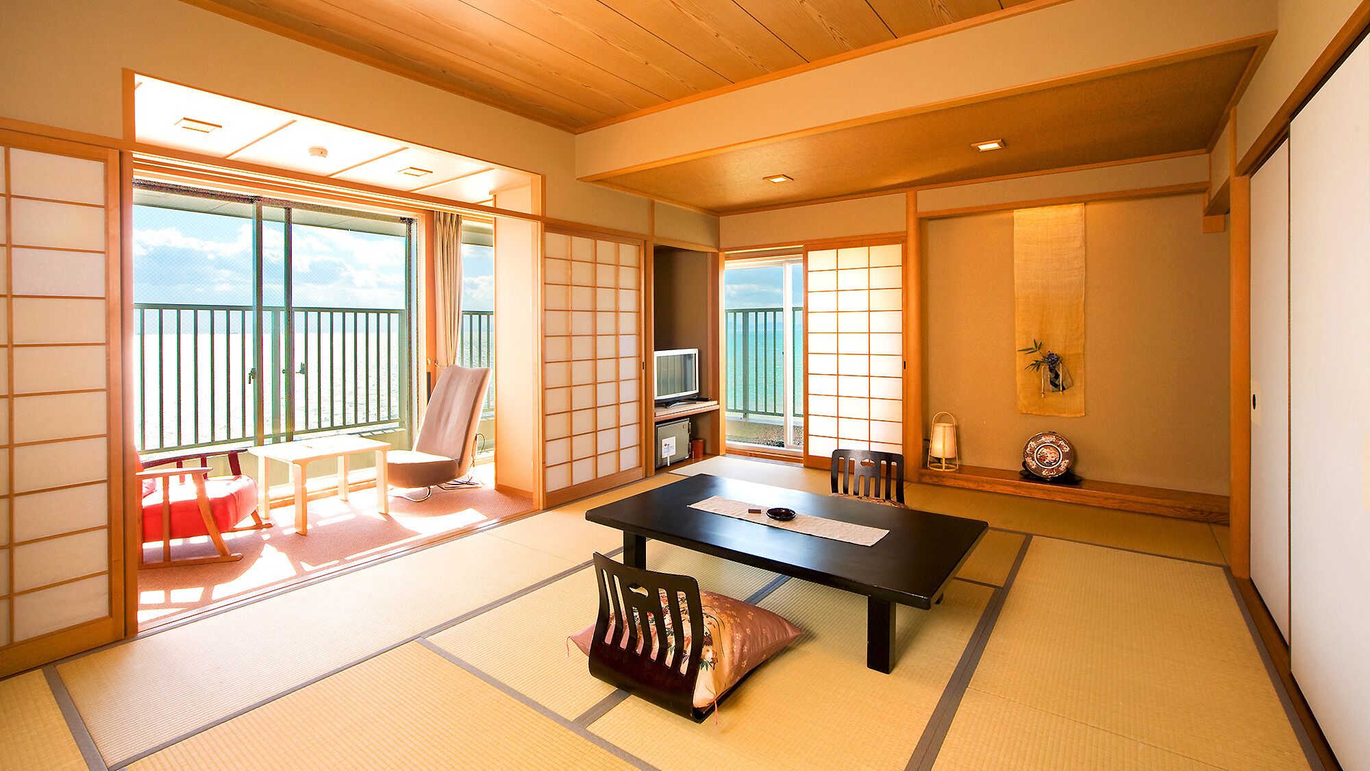 Een traditionele Japanse kamer met tatami vloerbedekking, een lage tafel, een stoel en schuifdeuren.