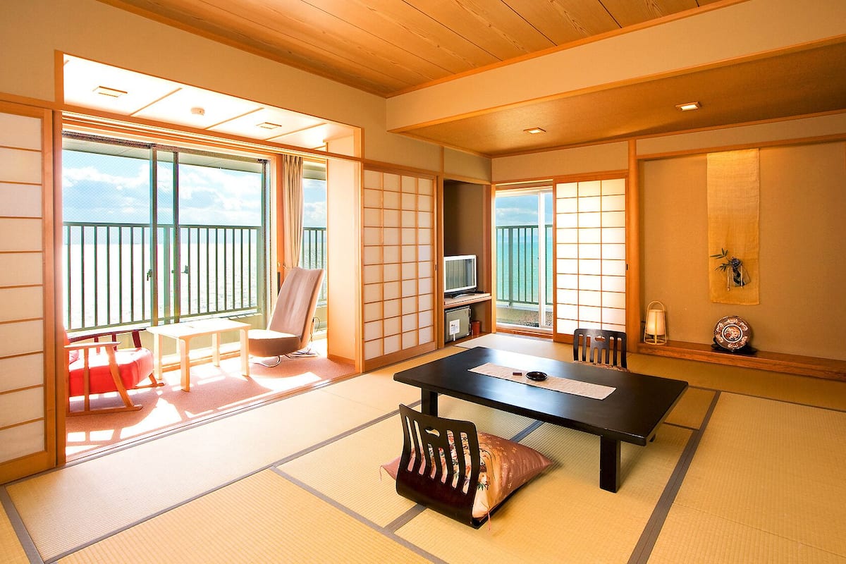 Een traditionele Japanse kamer met tatami vloerbedekking, een lage tafel, een stoel en schuifdeuren.