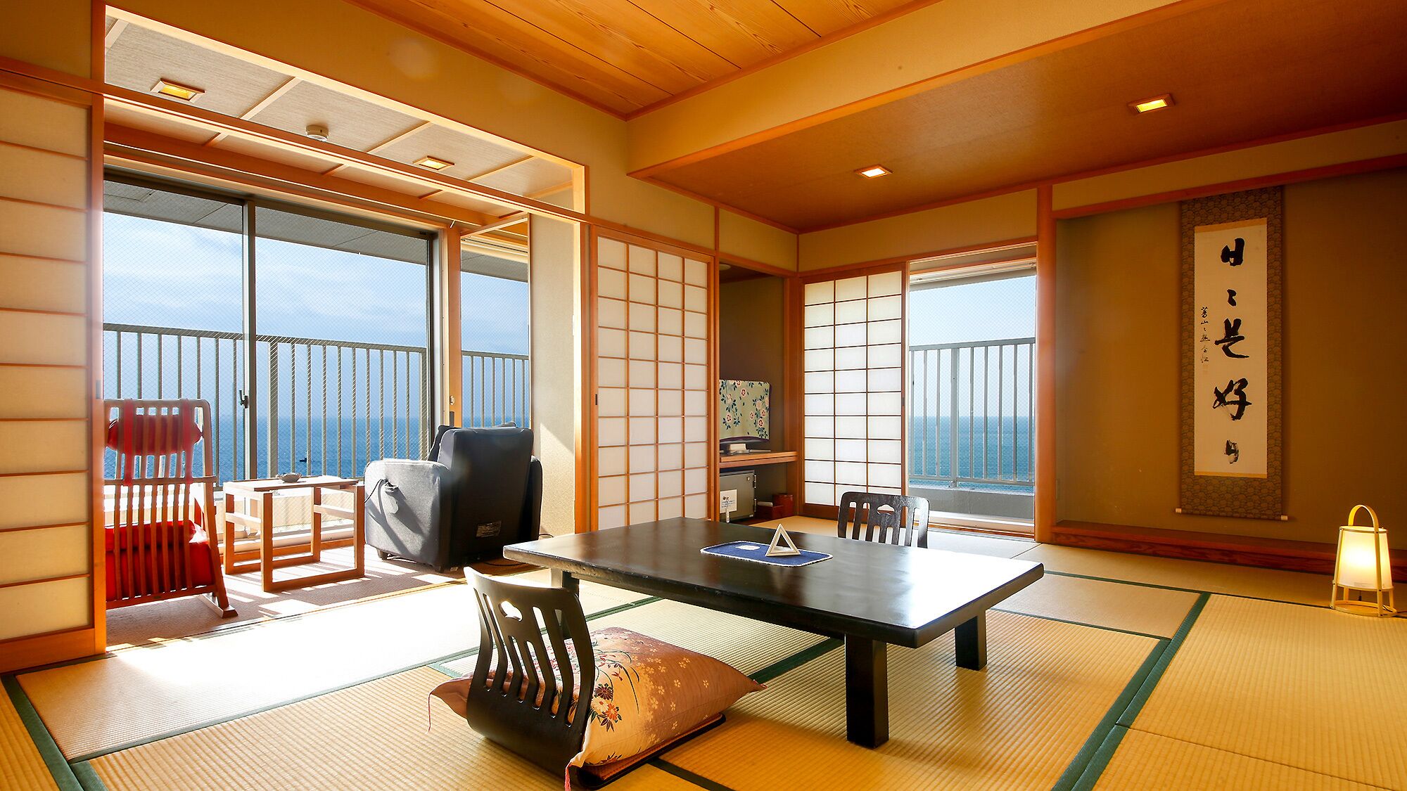 Een traditionele Japanse kamer met tatami vloerbedekking, een lage tafel, stoelen en schuifdeuren.