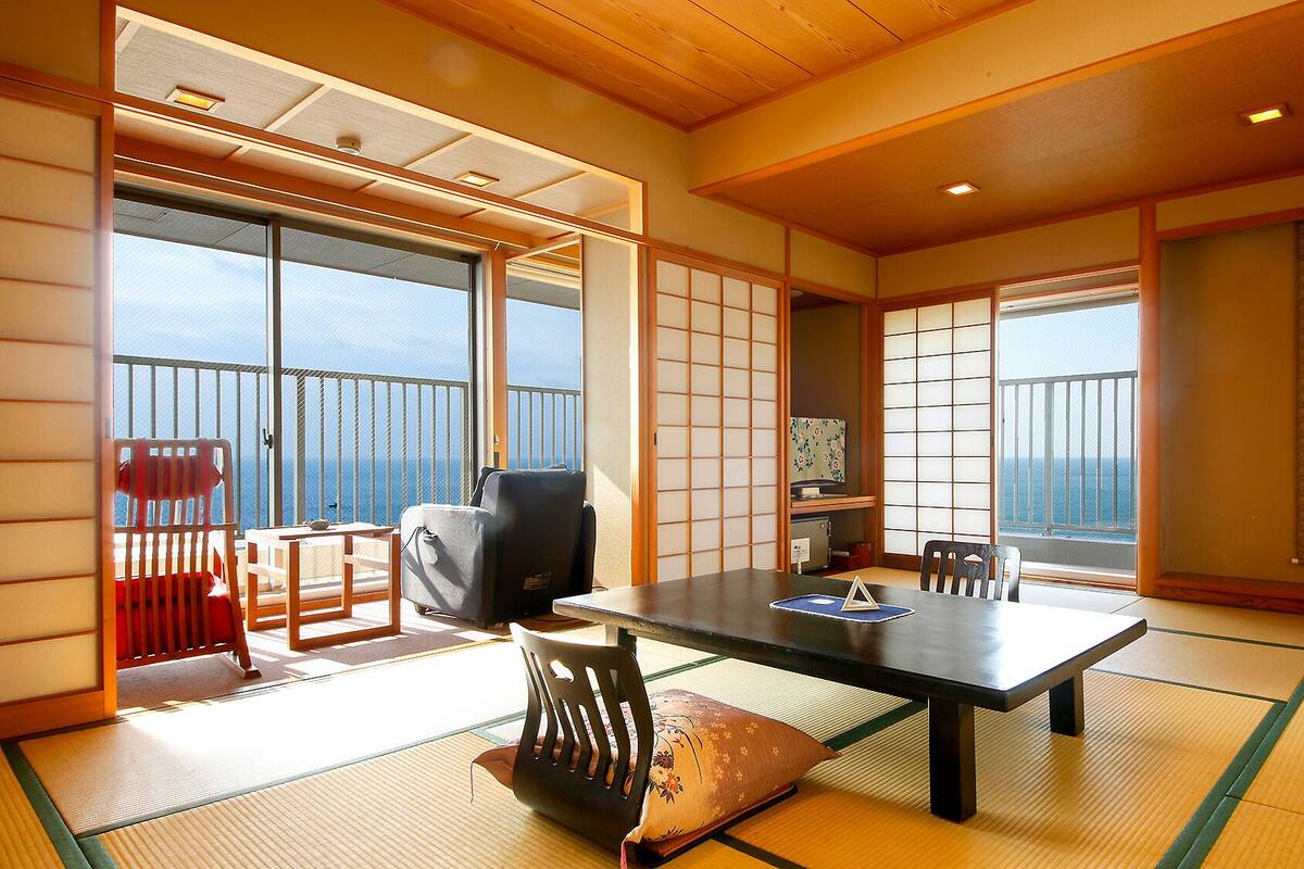 Een traditionele Japanse kamer met tatami vloerbedekking, een lage tafel, stoelen en schuifdeuren.