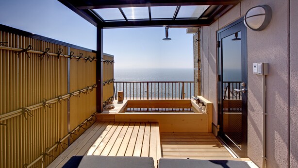 Ein Balkon mit Holzboden, zwei Lounge-Sesseln, einer kleinen Sitzecke und Meerblick.
