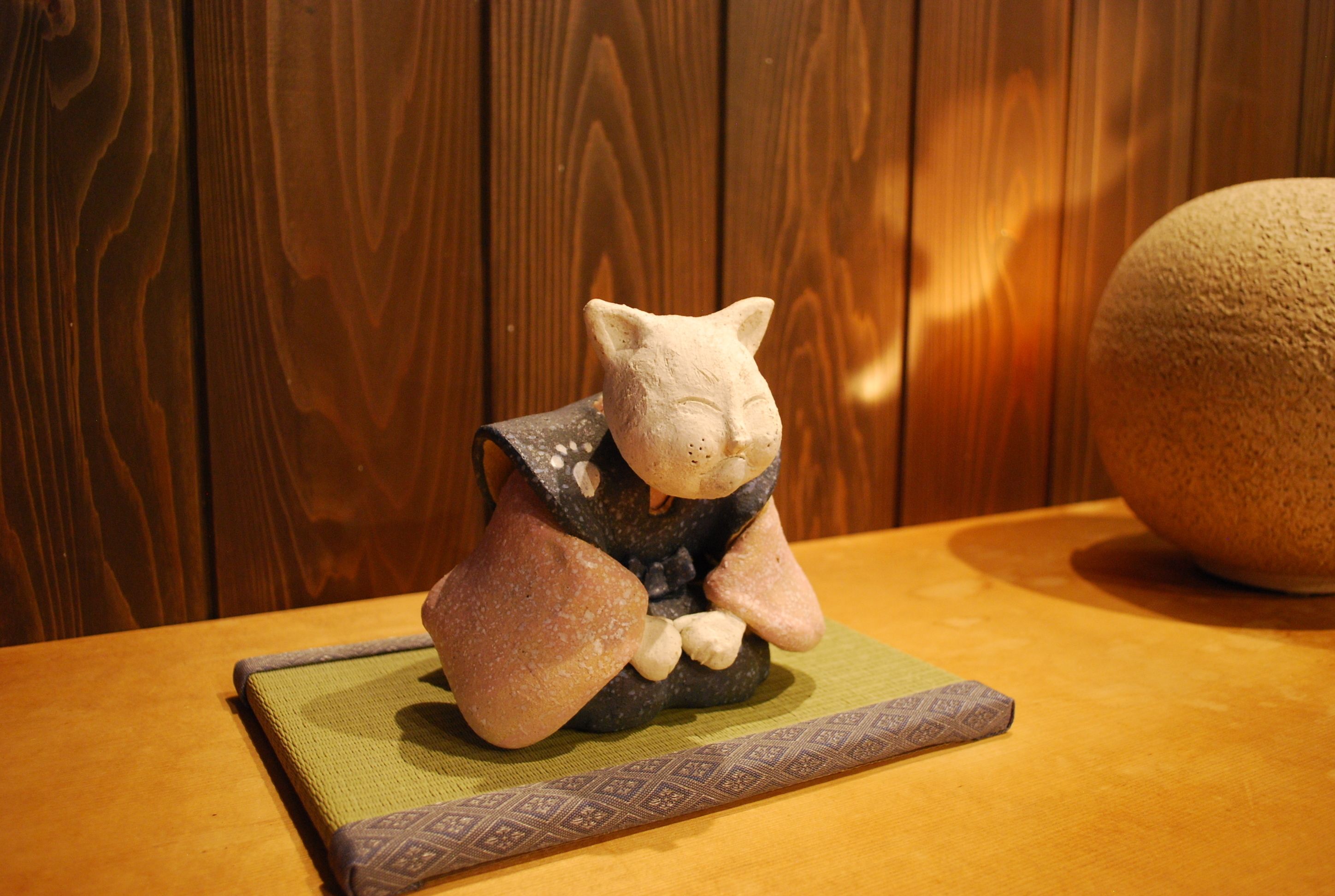 A ceramic cat figurine on a table with a patterned mat.