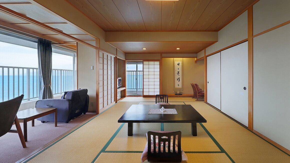 Een traditionele Japanse kamer met tatami vloeren, een laag tafeltje van tatami matten, een bank en schuifdeuren.