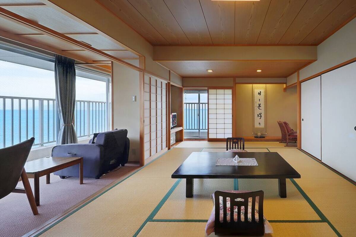 Een traditionele Japanse kamer met tatami vloeren, een laag tafeltje van tatami matten, een bank en schuifdeuren.