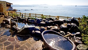 Un área empedrada con una amplia pila de agua, cerca de una valla de madera y vistas al mar.