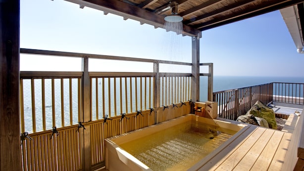 Una terraza de madera con un jacuzzi y vista al océano.
