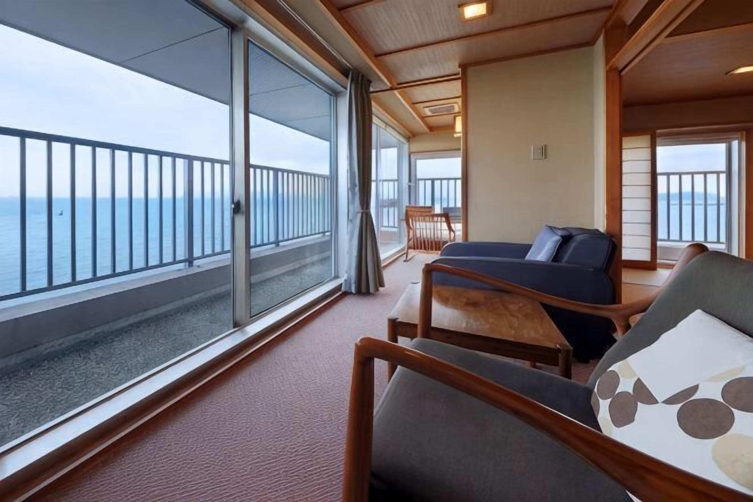 Een balkon met uitzicht op zee, een bank en een tafel.