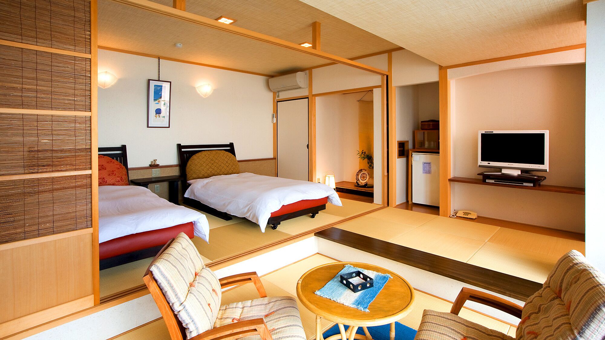 Een hotelkamer met twee bedden, een televisie, een kleine koelkast en een spiegel die de kamer weerspiegelt.