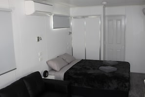 A modern bedroom with a large bed, a bedside table, a chair, and a wardrobe.