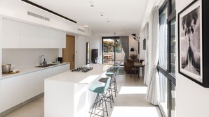 Une cuisine moderne dotée d’un îlot central, de tabourets de bar et d’un coin repas avec une table et des chaises.