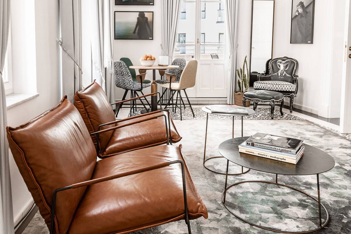 Una sala de estar moderna con un sofá de cuero, una mesa de centro y un comedor con sillas y una mesa.
