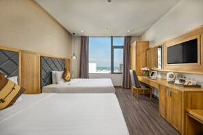 A hotel room with two beds, a desk with a computer, a TV, and a large window with a city view. - Grand Sunrise Boutique Hotel (Da Nang)