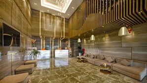 A spacious lobby with a modern design, featuring a large sofa, a coffee table, and a reception desk.