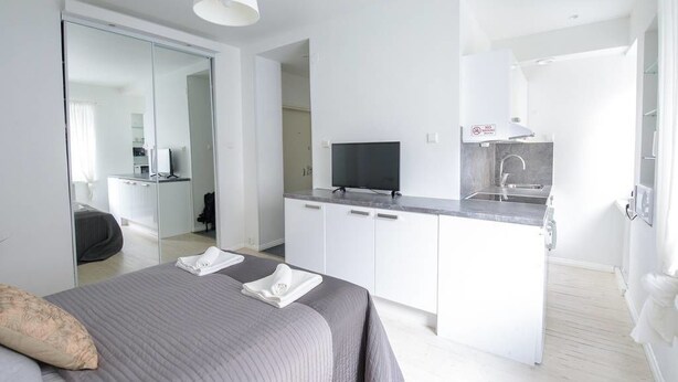 Ein modernes Hotelzimmer mit Bett, Fernseher, Küchenzeile und Badezimmer.