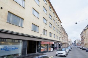 Une vue de rue avec un immeuble doté de nombreuses fenêtres et un magasin dont l’enseigne est visible.