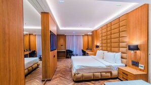 A modern hotel room with a large bed, a desk, a chair, and a TV. - Hotel Grand Dhillon (Durg)