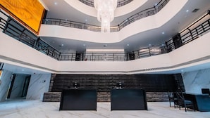 A multi-level atrium with a grand chandelier, marble floors, and a central reception area. - Hotel Grand Dhillon (Durg)