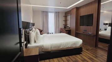 Una habitación de hotel con una cama grande, un escritorio, una silla, un televisor y un espejo.