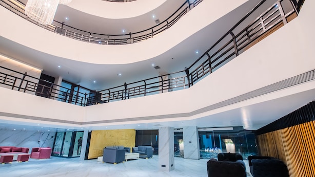 A multi-level hotel lobby with marble floors, modern seating, and a glass elevator. - Hotel Grand Dhillon (Durg)