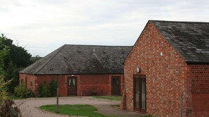 A brick building with a sloped roof, a door, and a small window. - Coldham Cottages (Bedford)