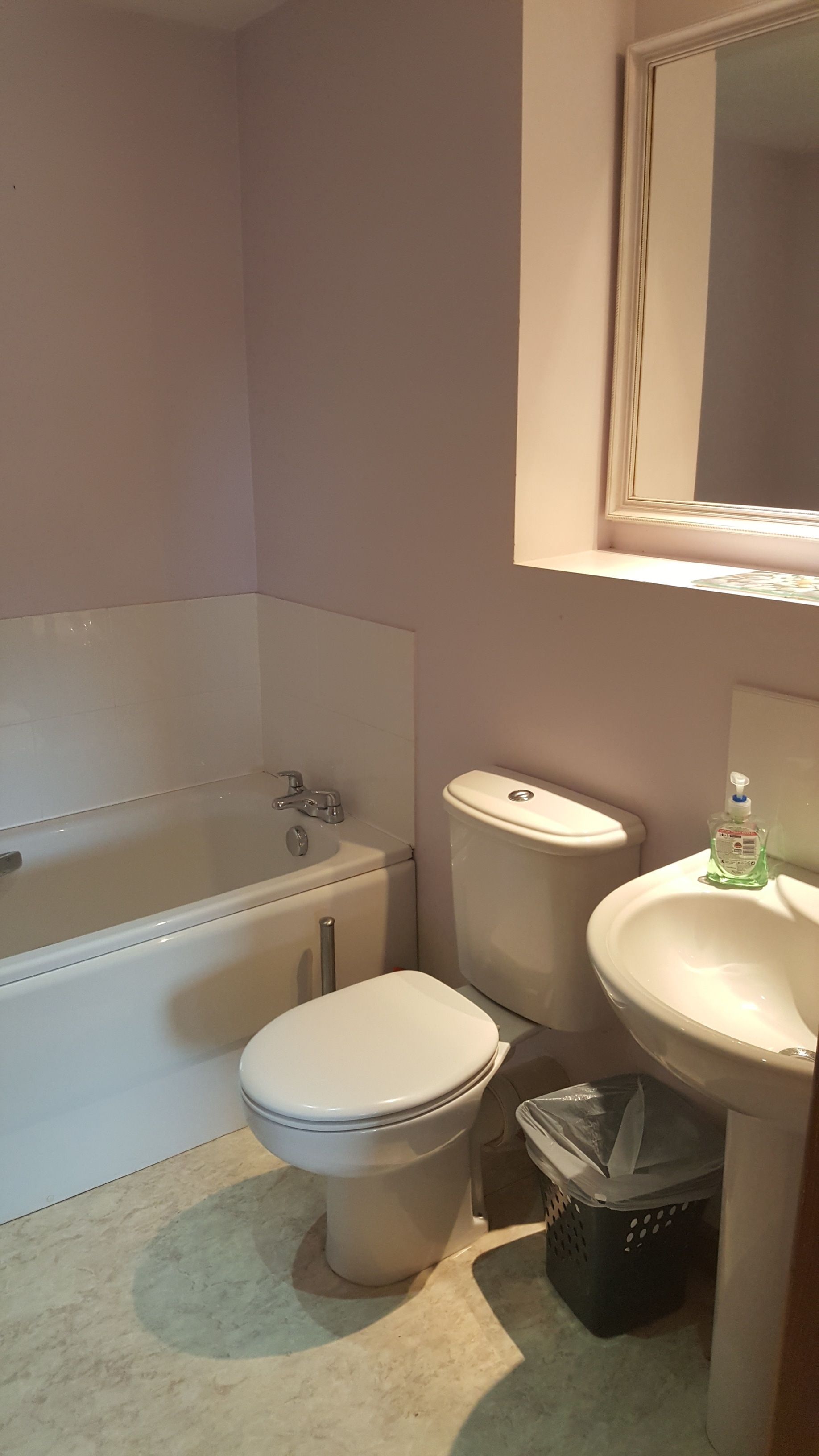 Ein Badezimmer mit Badewanne, Toilette, Waschbecken und Mülleimer.