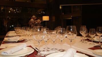 Una mesa de comedor dispuesta con varias copas de vino, platos y cubiertos, lo que sugiere una cena formal.