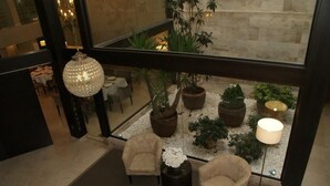 A spacious indoor area with a seating arrangement, potted plants, and a hanging light fixture. - Hotel Paloma (Tomelloso)