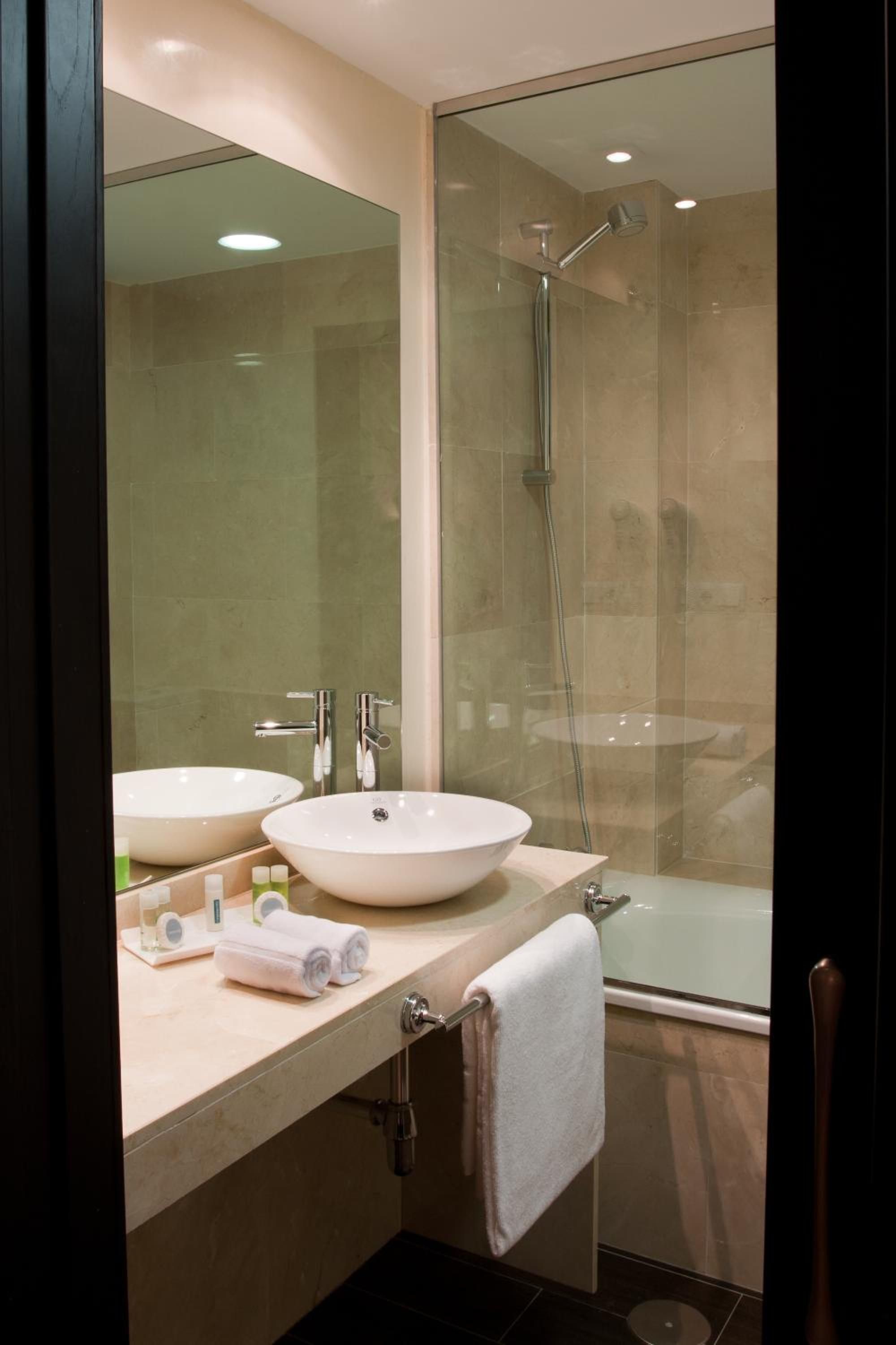 A modern bathroom with two sinks, a glass shower enclosure, and a bathtub.