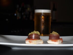 A plate with two small appetizers and a glass of beer. - Hotel Paloma (Tomelloso)