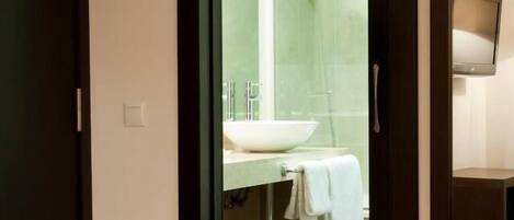 A modern bathroom with a glass shower enclosure, a sink, and a towel hanging on the wall.