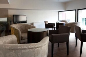 Una sala de estar moderna con un sofá, sillones, una mesa de centro y un televisor de pantalla plana montado en la pared.