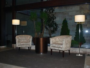 Un hall con dos sillones, una planta en maceta y una lámpara de pie.