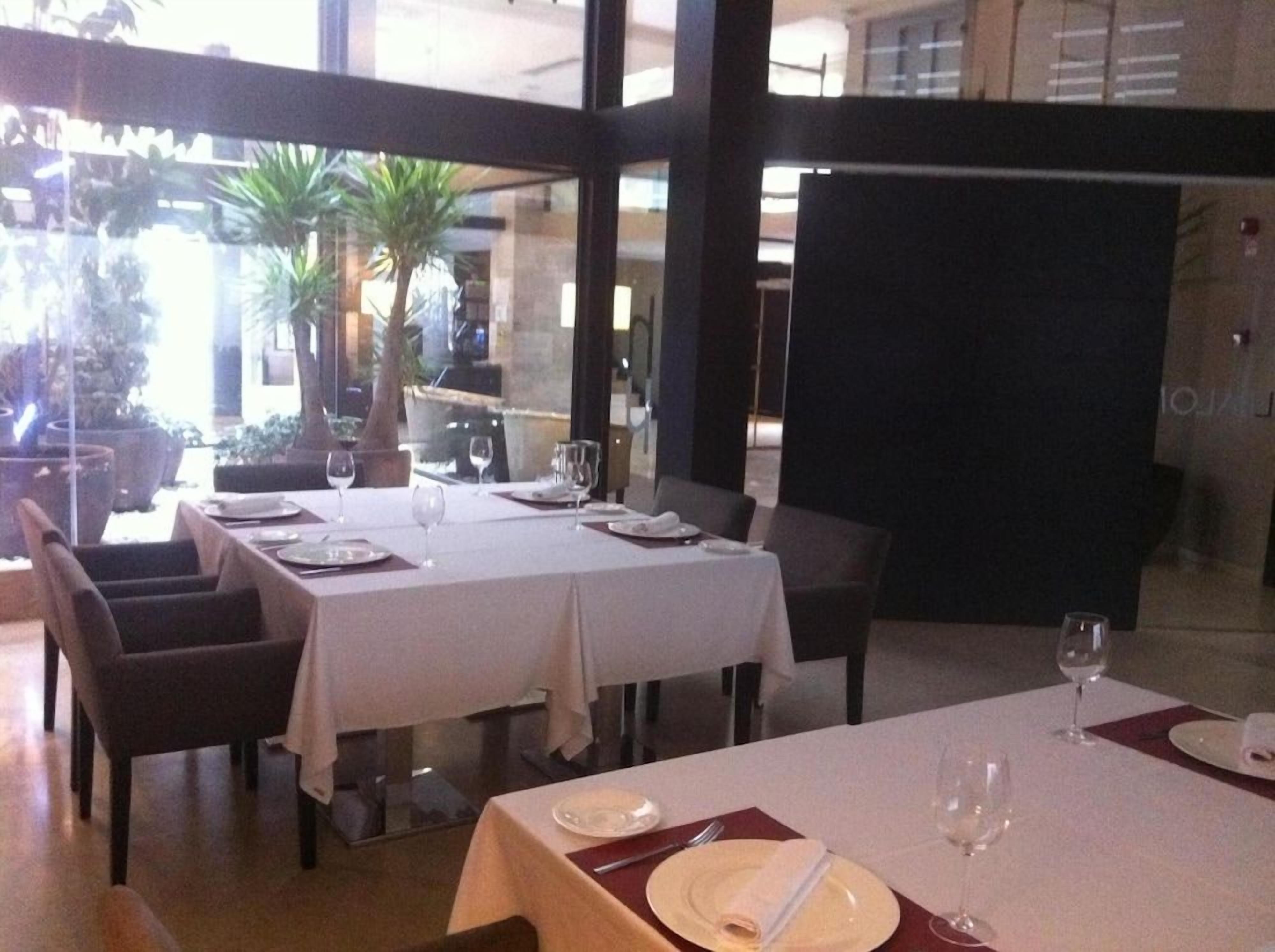 Zona pranzo con tavoli apparecchiati per due, con tovaglie bianche e posate disposte con cura.