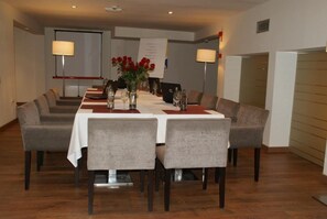 A conference room with a long table, grey chairs, and a white tablecloth. - Hotel Paloma (Tomelloso)