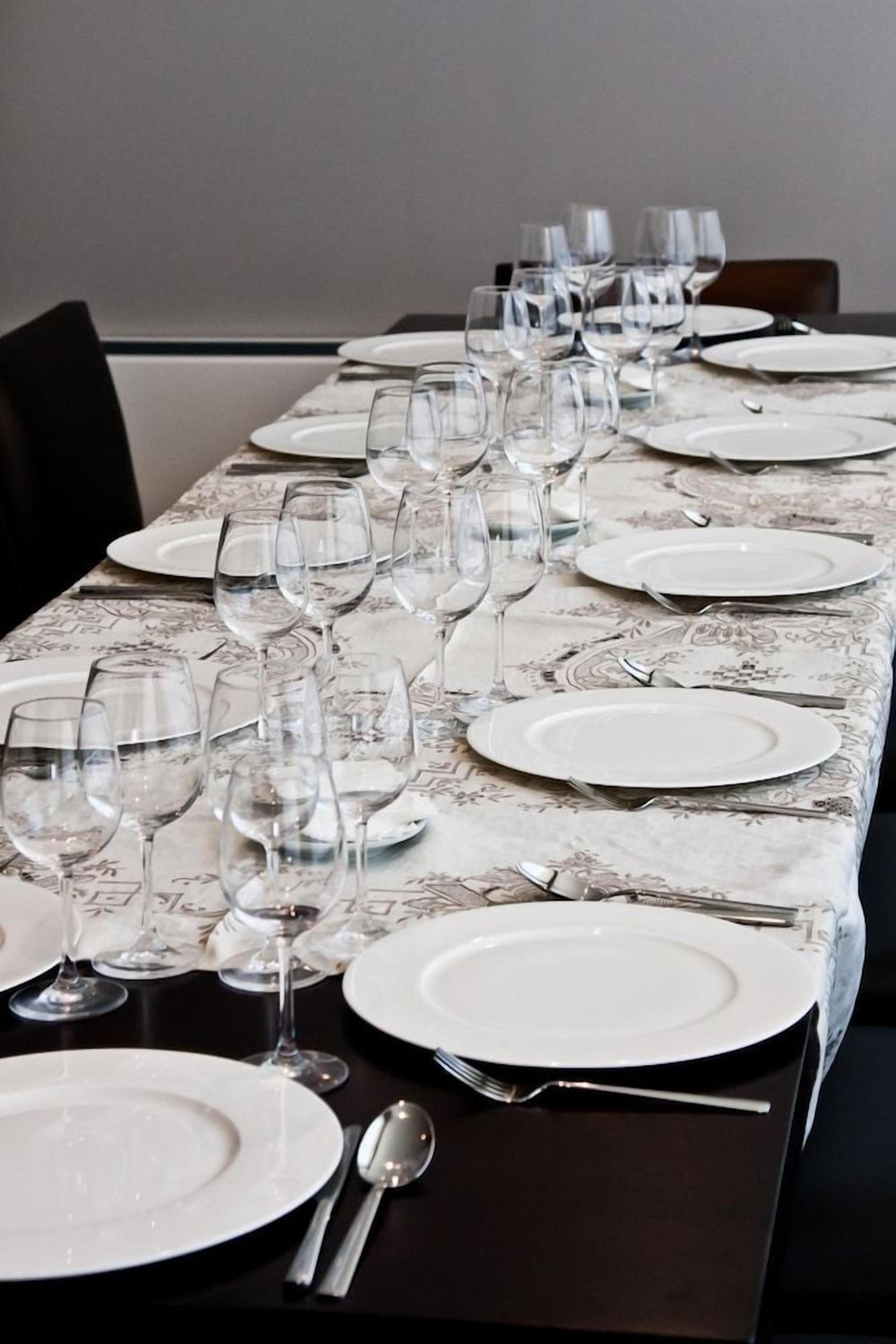 Una mesa de comedor dispuesta con varios platos, vasos y cubiertos.
