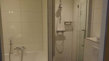A modern bathroom with a glass shower enclosure, a separate bathtub, and a visible towel rack.